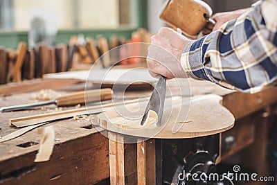 Instrument worker using traditional tools to carve a mandolin Stock Photo
