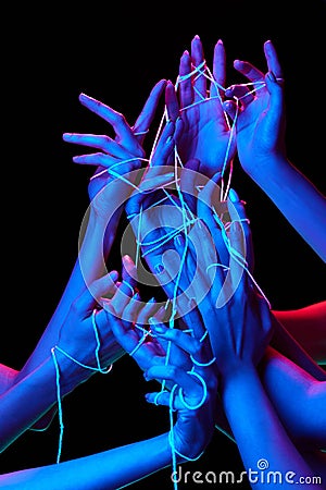 Hands interact with luminescent threads in multicolored neon lighting against black studio background, symbolizing Stock Photo
