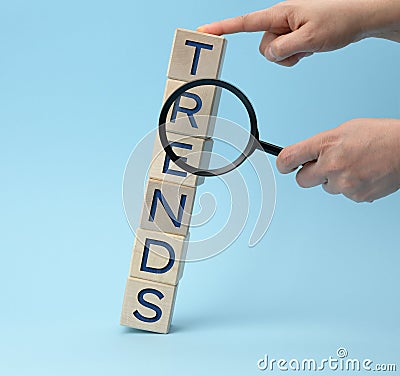 Hands are jerking a magnifying glass and wooden cubes with the inscription trends Stock Photo
