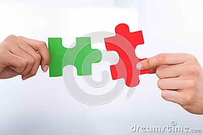 Hands joining puzzle pieces Stock Photo