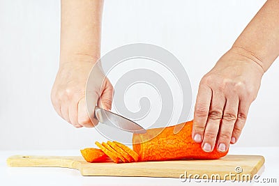 Hands with a knife slices carrots on a cutting board Stock Photo