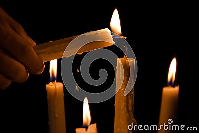 Hands light up the candles with another candle Stock Photo
