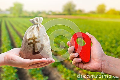 Hands with location pin and turkish lira money bag. Land market. Estimation cost of plots. Transport and construction industry. Stock Photo