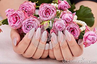 Hands with long artificial manicured nails colored with nail polish with silver glitter Stock Photo