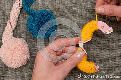 Hands Looping Yellow Yarn Around Pom-Pom Maker Stock Photo
