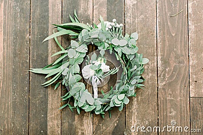 Hands making wedding wreath from eucalypthus and flowers and groom boutonniere from white flowers and greenery on wooden Stock Photo