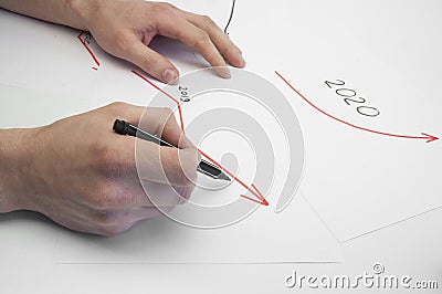 Hands of a male businessman write on a white sheet a growth graph. Growth arrow in 2020. On a white background. Stock Photo