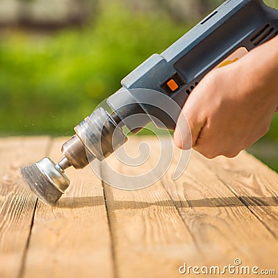 Hands man with electrical rotating brush metal disk sanding a piece of wood Stock Photo