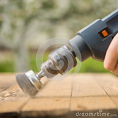 Hands man with electrical rotating brush metal disk sanding a piece of wood Stock Photo