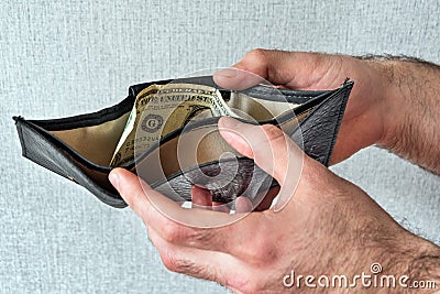 Hands of a man holding an open wallet in which one dollar lies Stock Photo