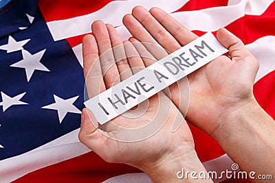 Hands of a man holding a sign with the inscription I have a dream. Against the background of the American flag. Stock Photo