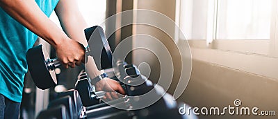 Hands of man lifting dumbbells on rack in gym or fitness Stock Photo