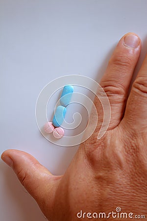 Hands of a man next to pills that symbolize a penis with an erection. Metaphor of male virility. Medicine related to male Stock Photo