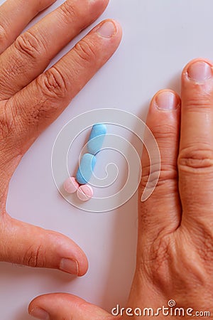 Hands of a man next to pills that symbolize a penis with an erection. Metaphor of male virility. Medicine related to male Stock Photo