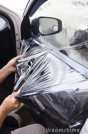 Hands of man removing old car window film Stock Photo