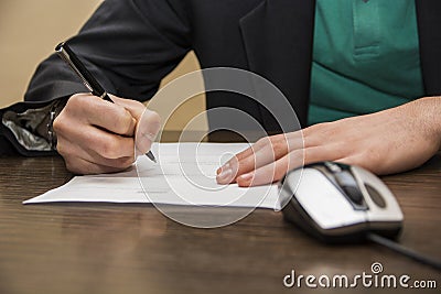 Hands of man signing a sheet of paper or document Stock Photo