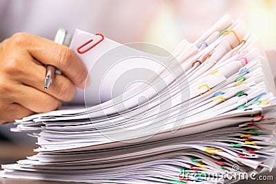 Hands of a man in a white shirt searching for contract agreement documents in Stack of Group report papers clipped in color clips Stock Photo