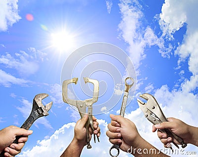 The hands of many mechanic holding instruments with blue sky background,clouds and sun in the daytime. Mechanic success and Tools Stock Photo