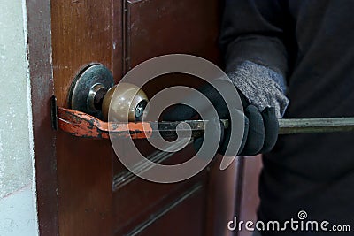 Hands of Masked thief with balaclava using crowbar to breaking into a house at night time. Crime concept. Stock Photo