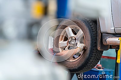 Hands of mechanic with tool, changing tyre of car at auto repair service center Stock Photo