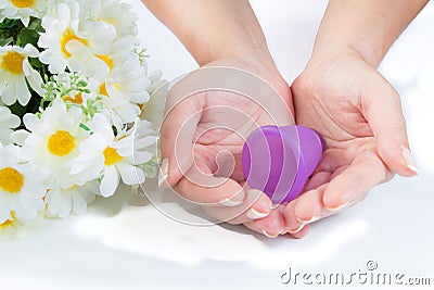 Hands, menstrual cup and flowers. Stock Photo