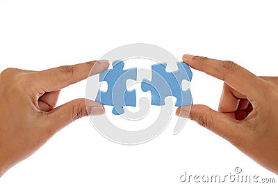 Hands merging two jigsaw puzzle pieces against white Stock Photo