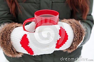 Hands in mittens with hearts holding cup Stock Photo
