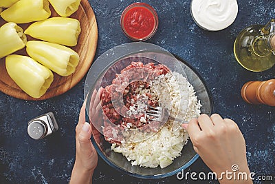 Hands mixing minced meat, chopped onion, boiled rice and seasons in the big glass bowl. Stock Photo