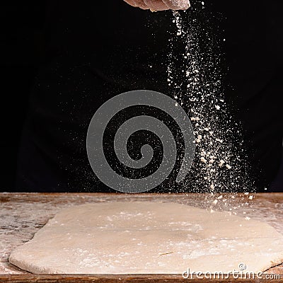 The hands of an old grandmother sprinkle with flour dough Stock Photo