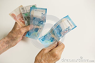 The hands of an old pensioner keep money of a large size. The hands of a man are old, decrepit. Stock Photo