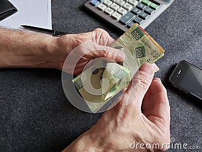 hands of an older man counting Mexican banknotes Stock Photo