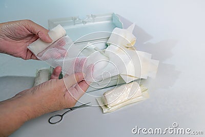 Hands of an older woman taking a sterile gauze bandage out of a first aid kit with medical supplies, health and medicine concept, Stock Photo