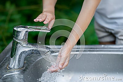 Hands open for drinking tap water. Pouring fresh healthy drink. Good habit. Right choice. Child washes his hand under the faucet Stock Photo