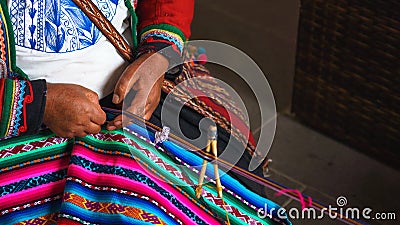 Close up of weaving in Peru. Cusco, Peru. Woman dressed in colorful traditional native Peruvian closing knitting a carpet with Stock Photo