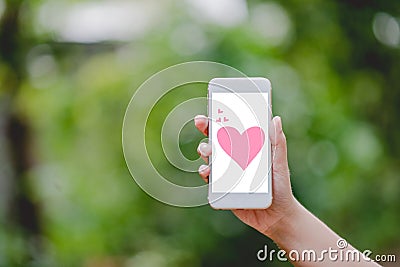 Hands and phones Pink heart screen Green nature Technology Concepts And to do business online. Stock Photo