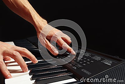 Hands of pianist play the keys of the electronic synthesizer on black background Stock Photo