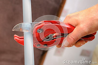 Hands plumbing with a cutter for plastic pipes. Stock Photo