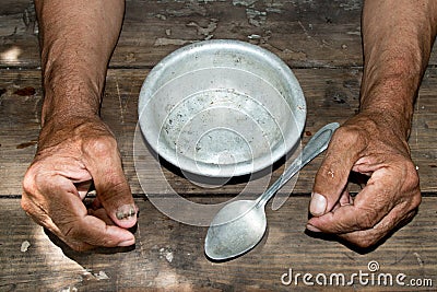 hands the poor old man& x27;s and empty bowl on wood background. The Stock Photo