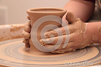 Hands of a potter, creating an earthen jar on pottery wheel. Stock Photo
