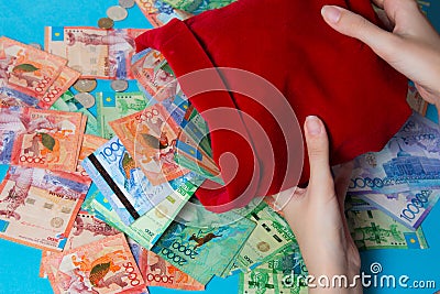 Hands pour out of the bag of tenge. Kazakhstan, KZ, KZT. A lot of money in a red bag. National currency, banknote. Bank, Finance, Stock Photo