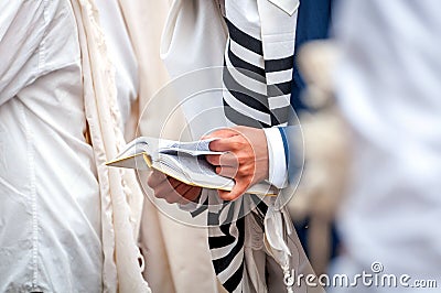 Hands and prayer book close-up. Orthodox hassidic Jews pray in a holiday robe and tallith Stock Photo