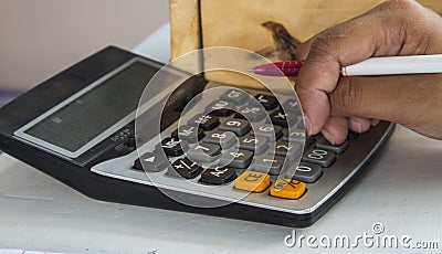 Hands are pressing the calculator to calculate the cost. Stock Photo