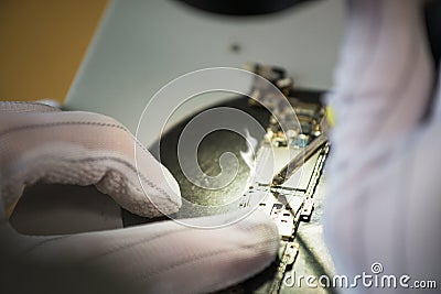 Hands of professional tech repairing small computer components on microscope table using Soldering iron. Closeup Stock Photo