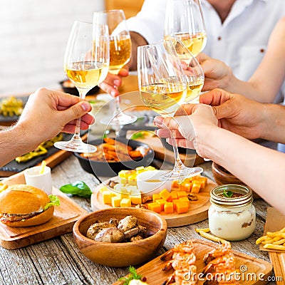 Hands with red wine toasting over served table with food. Stock Photo