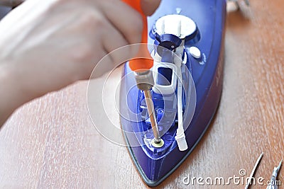 Hands repair iron. Concept: home appliance repair Stock Photo