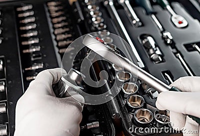 Hands of repairman in gloves close up with metal steel socket ratchet handle over toolbox, POV Stock Photo