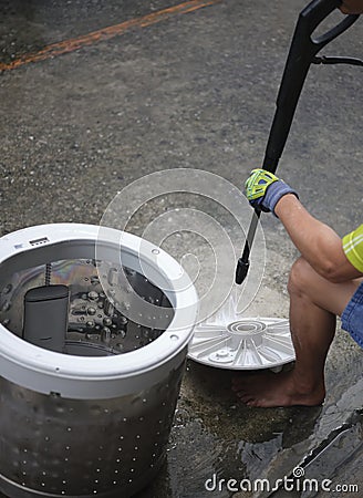 Hands of repairman using Water sprayer clean washing machine Stock Photo