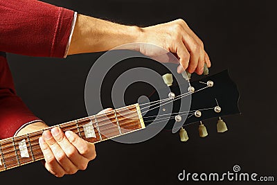 Hands of rock musician tunes the guitar on dark background Stock Photo