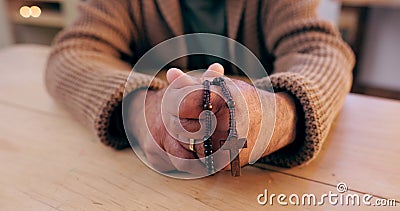 Hands, rosary and cross with closeup for faith, peace and hope at desk, home or praying for worship. Person, crucifix Stock Photo