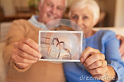 Hands of senior couple holding their youthful photo at home Stock Photo